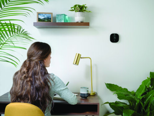 Young woman working from home checking the thermostat